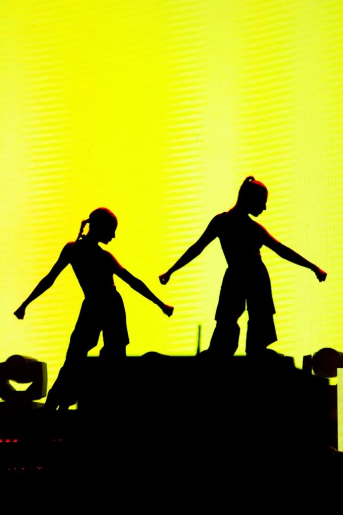 Silhouettes d’artistes découpées sur un écran jaune de scène