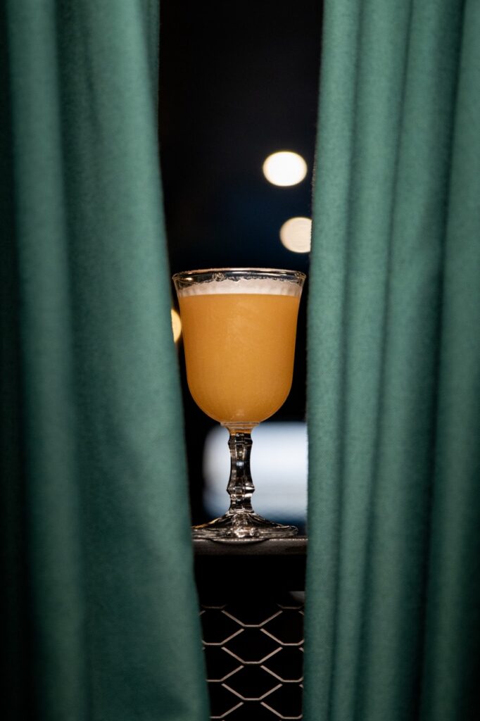 Cocktail ambré devant un rideau vert