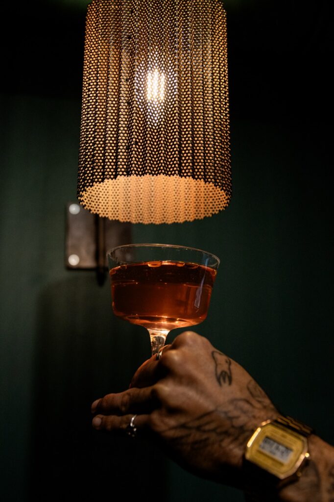 Cocktail tenu à la main dans la pénombre du bar