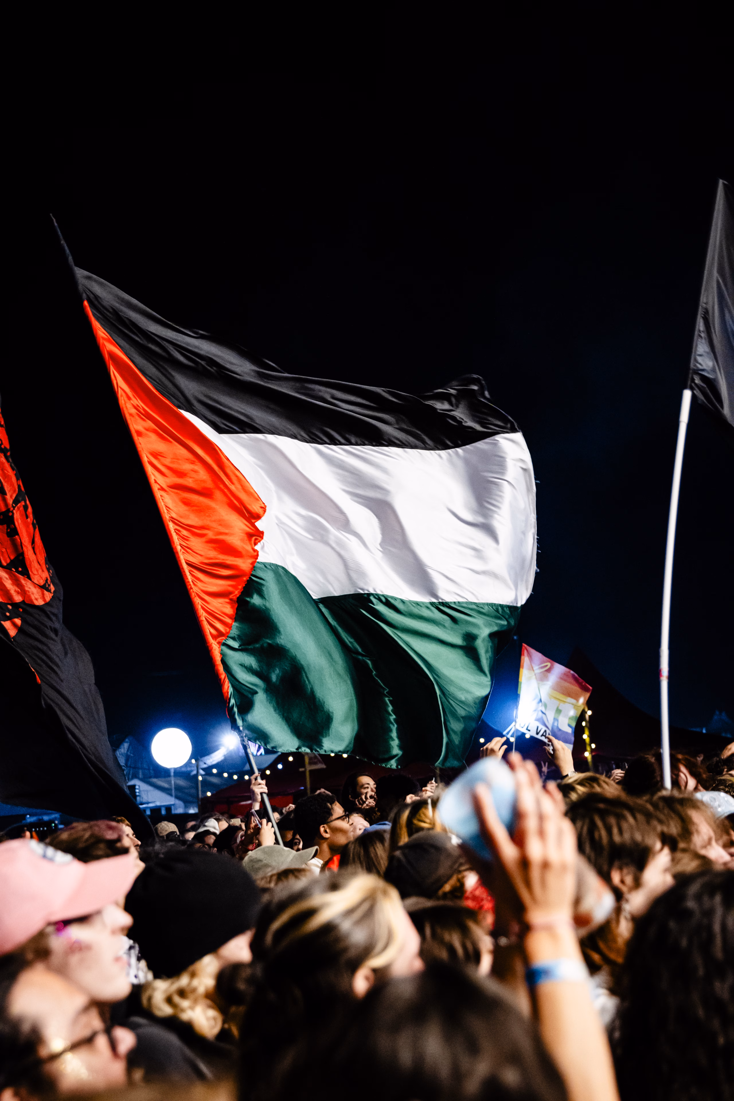 Drapeau palestinien brandi au-dessus de la foule pendant un concert nocturne