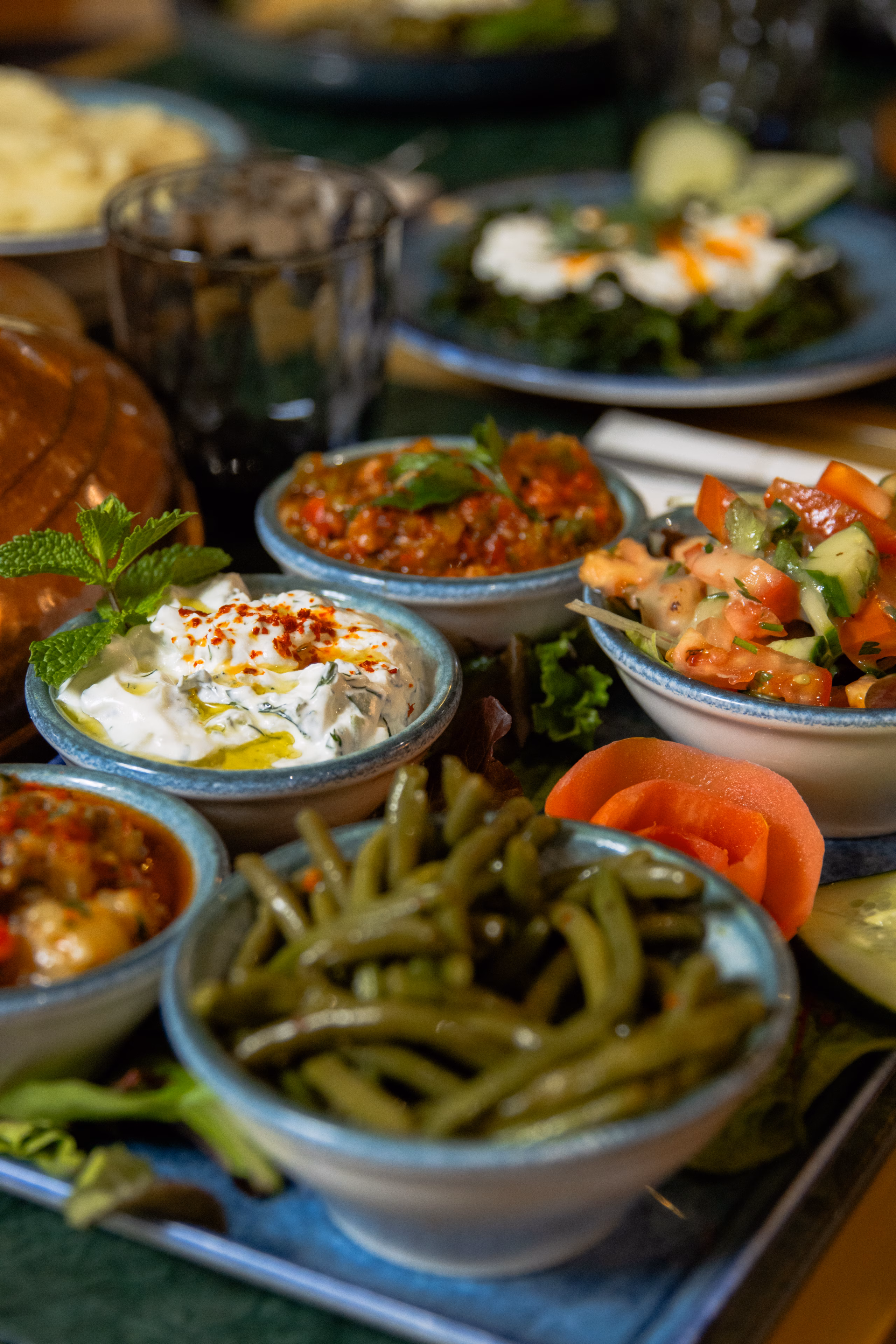 Assortiment de mezzés en bols : caviar d'aubergine, salade de tomates, haricots verts et yaourt aux herbes