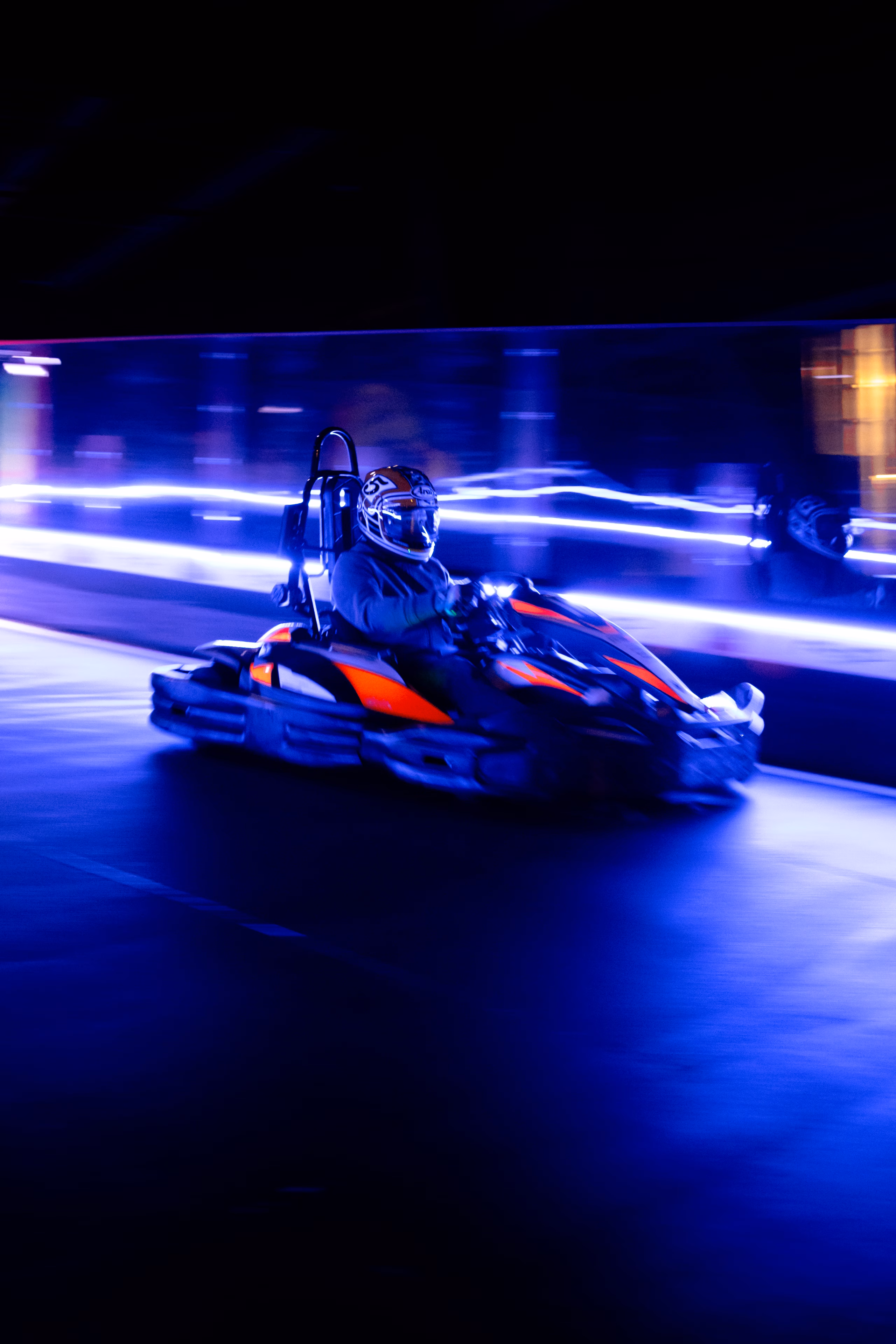 Kart lancé sur une piste couverte, traînées lumineuses bleues en arrière-plan