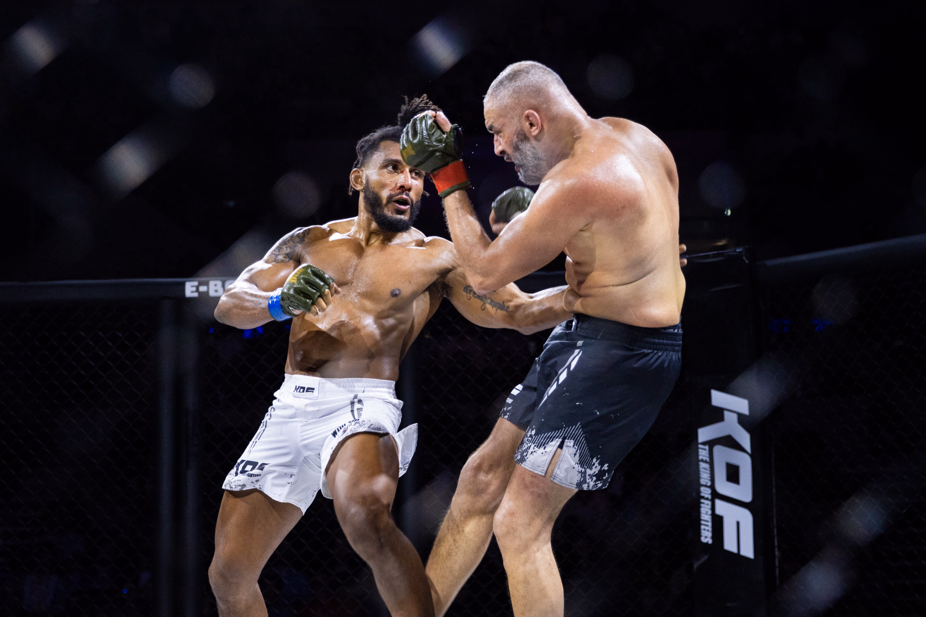 Deux combattants de MMA au corps à corps contre le grillage de la cage