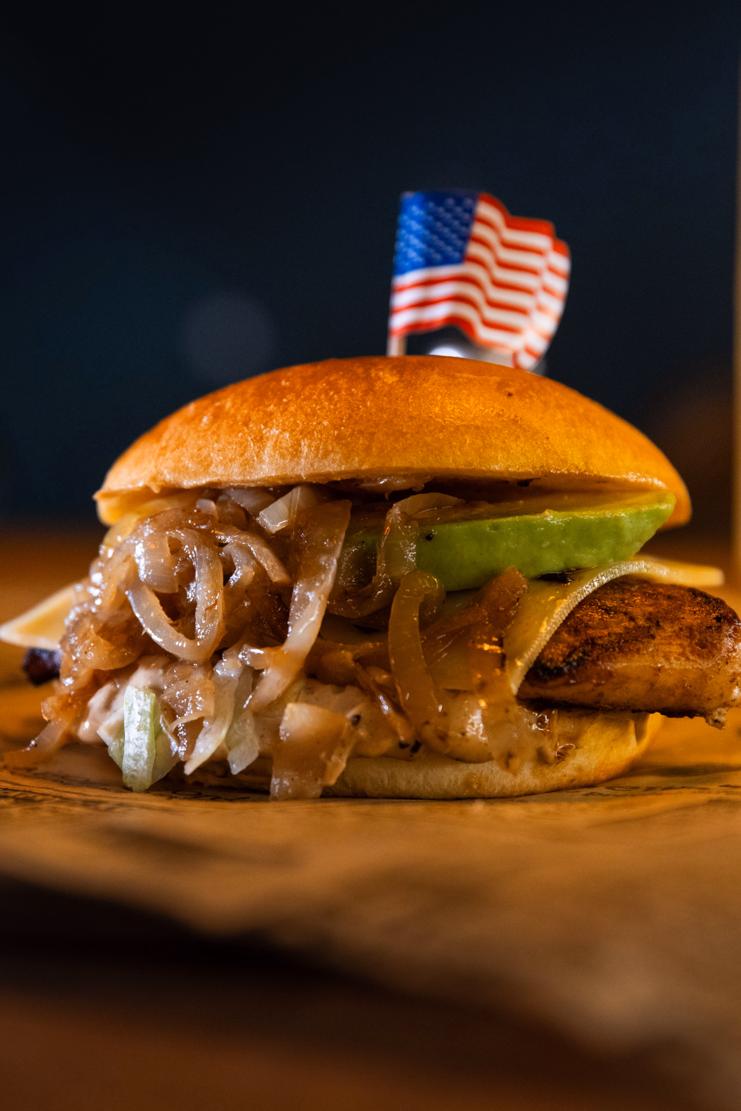 Burger de poulet à l'avocat et aux oignons confits, petit drapeau américain planté dessus
