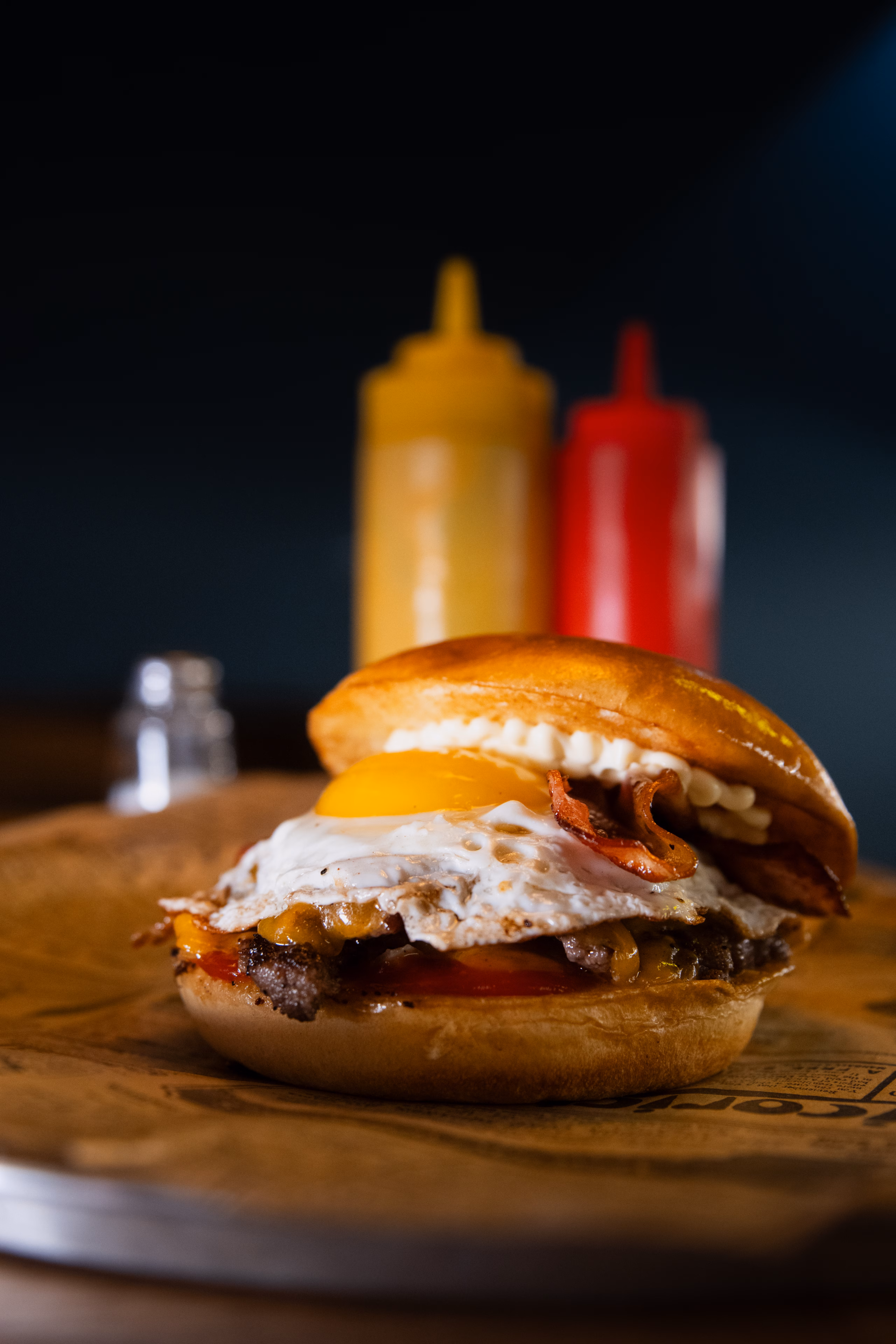 Burger à l'œuf au plat et au bacon posé sur une planche en bois
