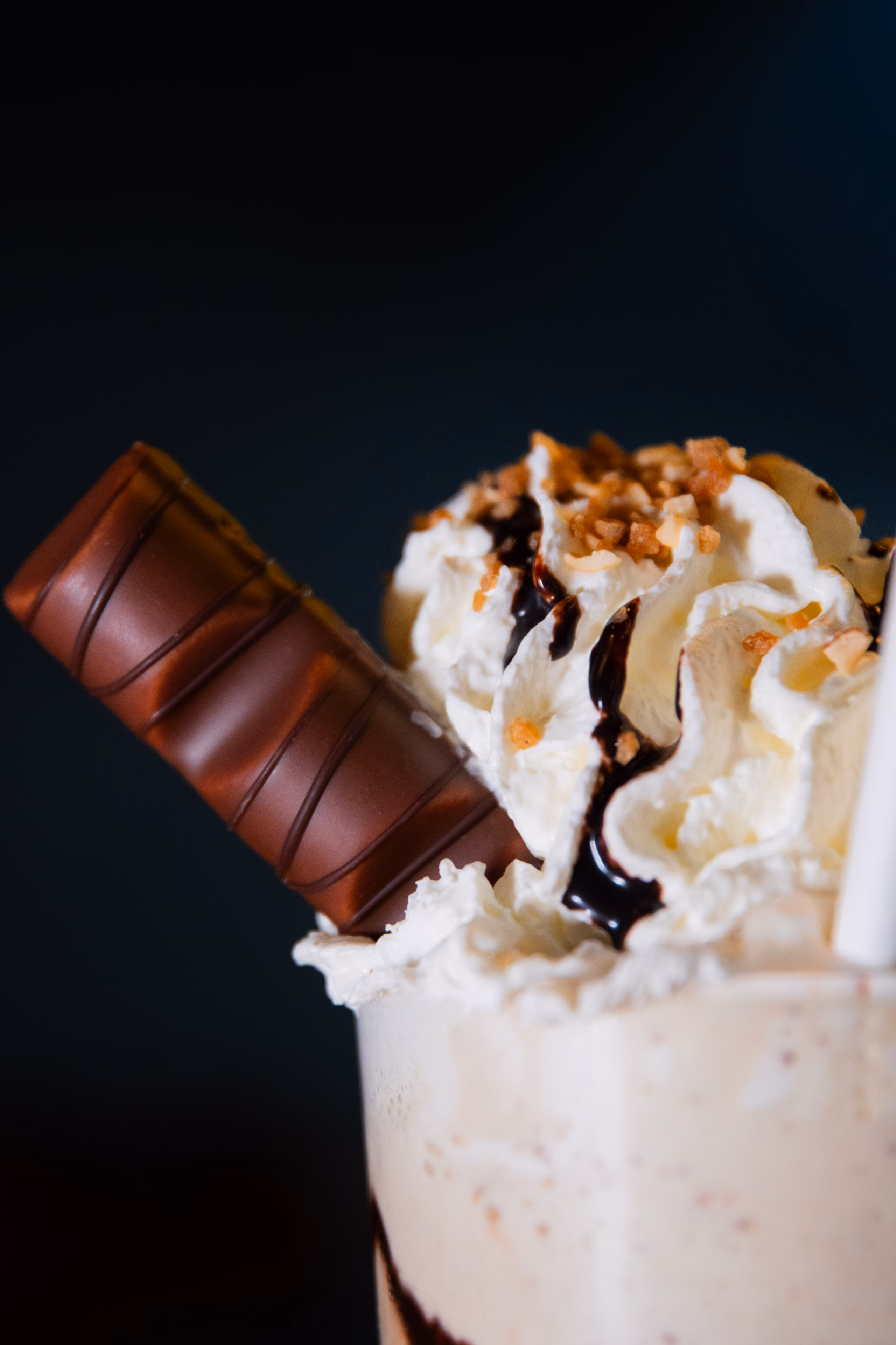 Milkshake surmonté de chantilly, de sauce chocolat et d'une barre chocolatée