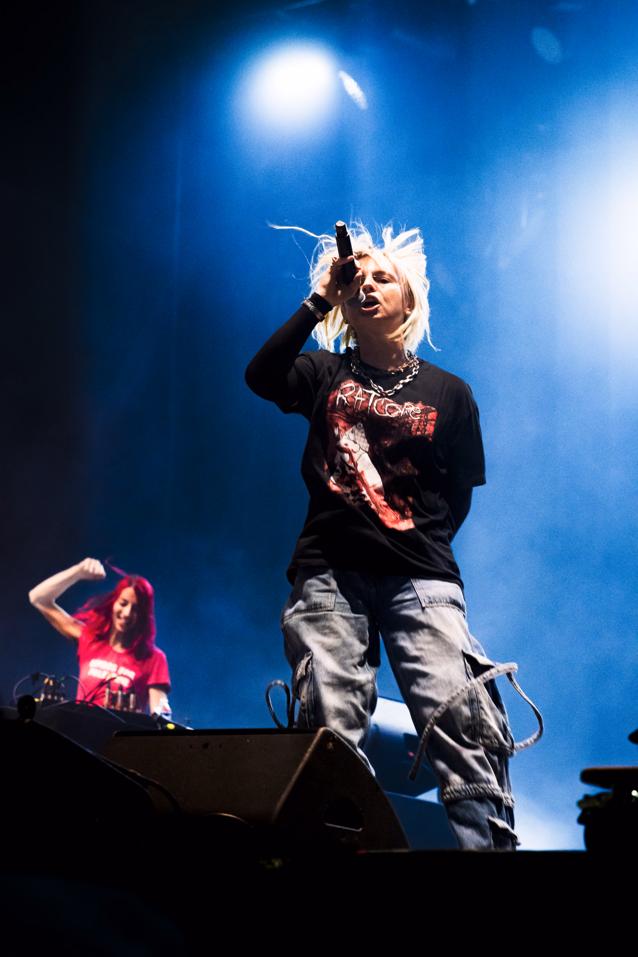 Chanteuse aux cheveux platine au micro, DJ en rose derrière elle