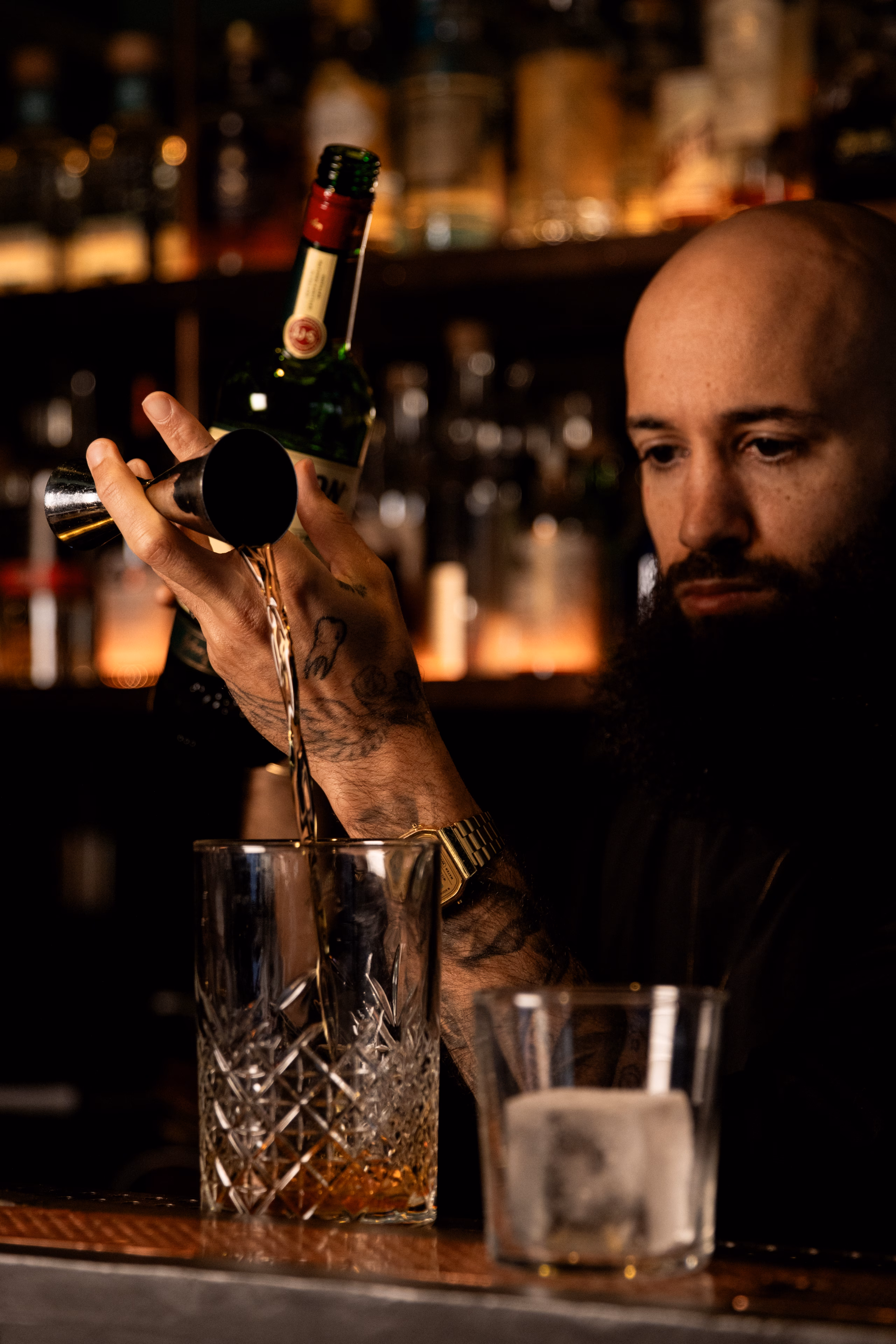 Barman versant une dose au jigger dans un verre taillé