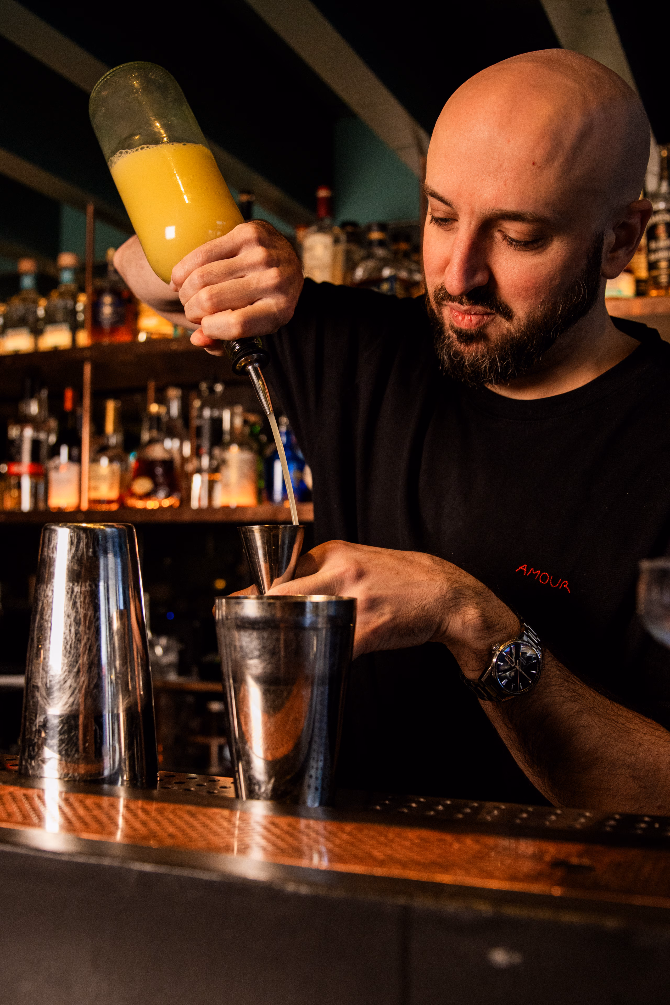 Barman versant un jus d'orange dans un shaker derrière le comptoir